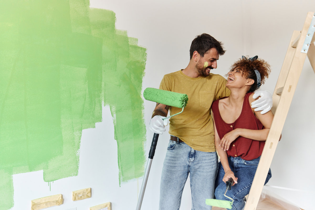 Happy couple talking while painting their new apartment.
